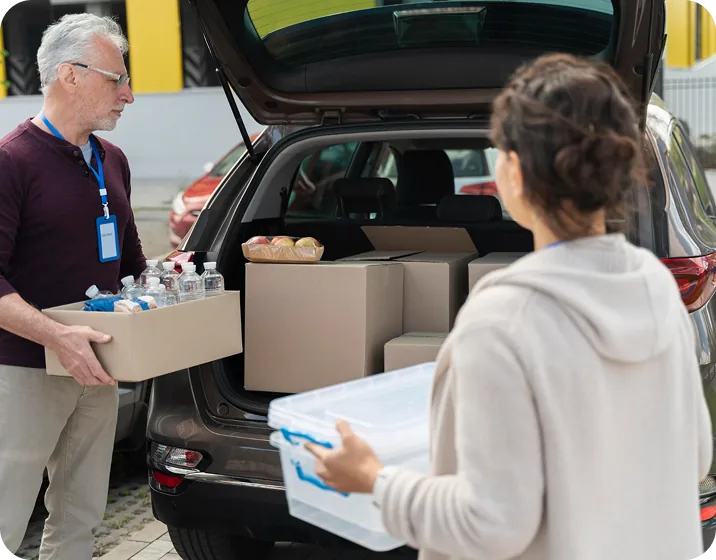 Volunteers loading supplies into a car trunk